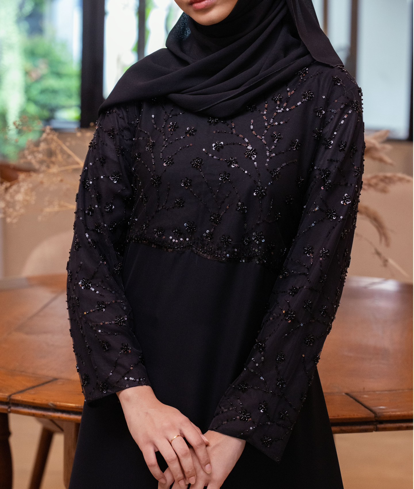 A premium black abaya featuring a sequin-embellished bodice and detailed sleeves for weddings and occasions.