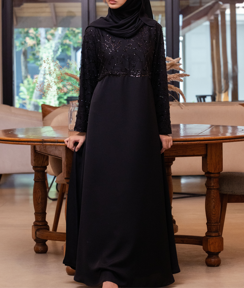 A premium black abaya featuring a sequin-embellished bodice and detailed sleeves for weddings and occasions.