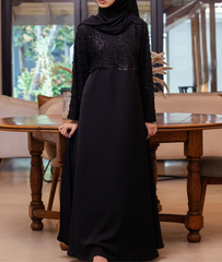 A premium black abaya featuring a sequin-embellished bodice and detailed sleeves for weddings and occasions.