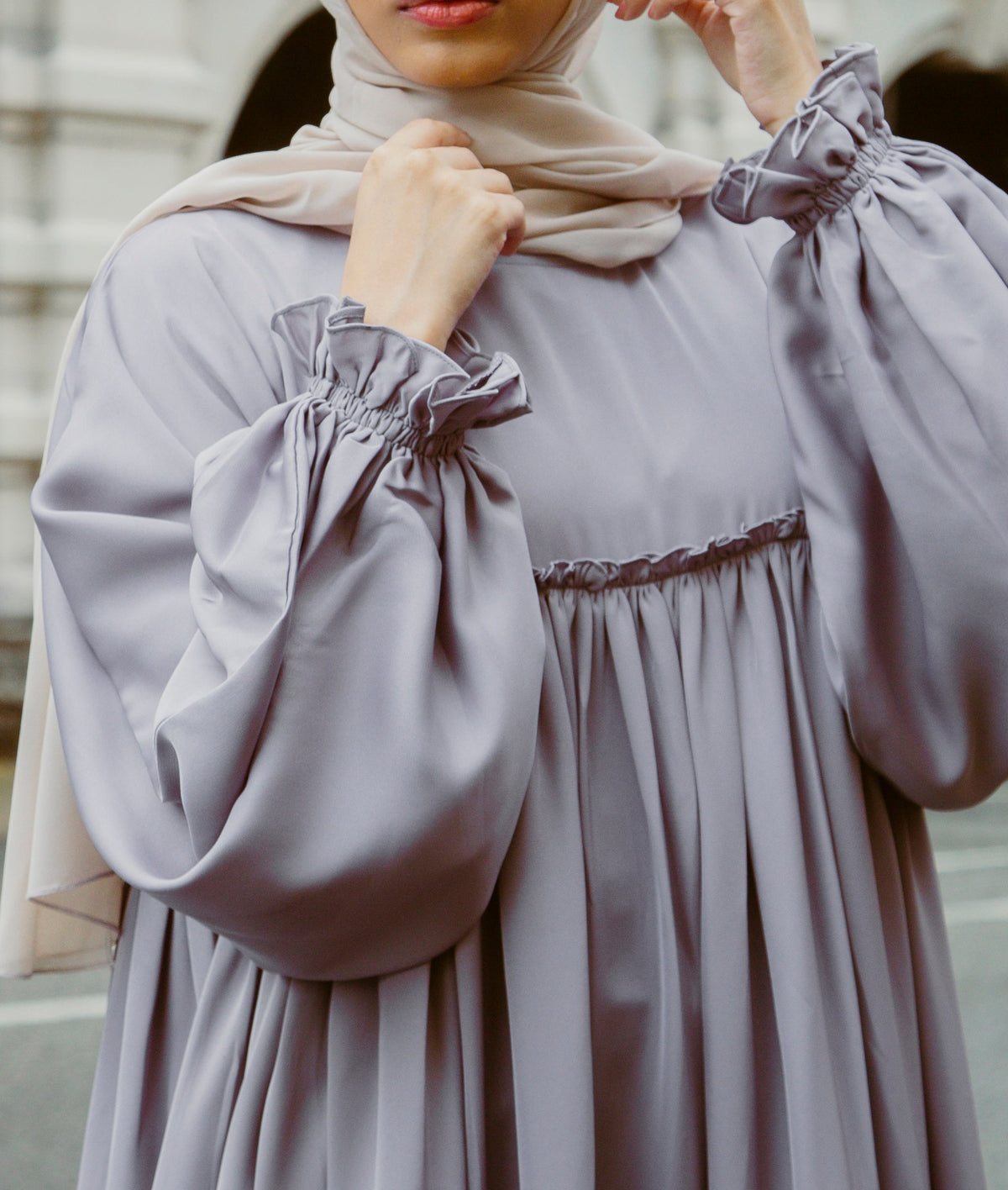 A woman wearing a modern mauve A-line abaya dress with a smocked bodice and ruffled sleeves from the latest abaya dresse collection 2026.